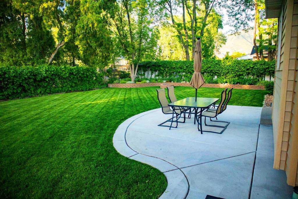 Backyard patio with outdoor dining set and manicured lawn