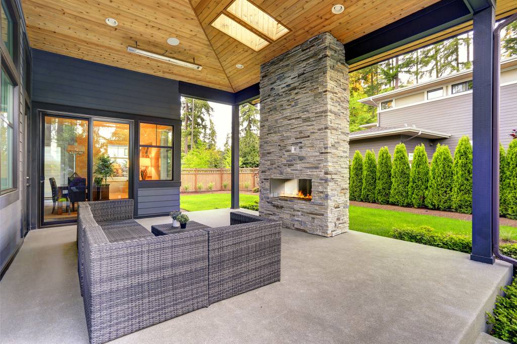 Covered patio with stone fireplace and wicker furniture